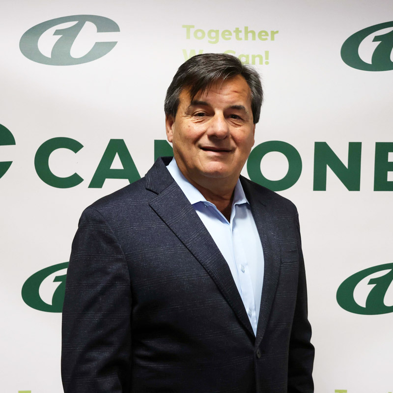 Male Can-One employee standing in front of Can-One logo wall